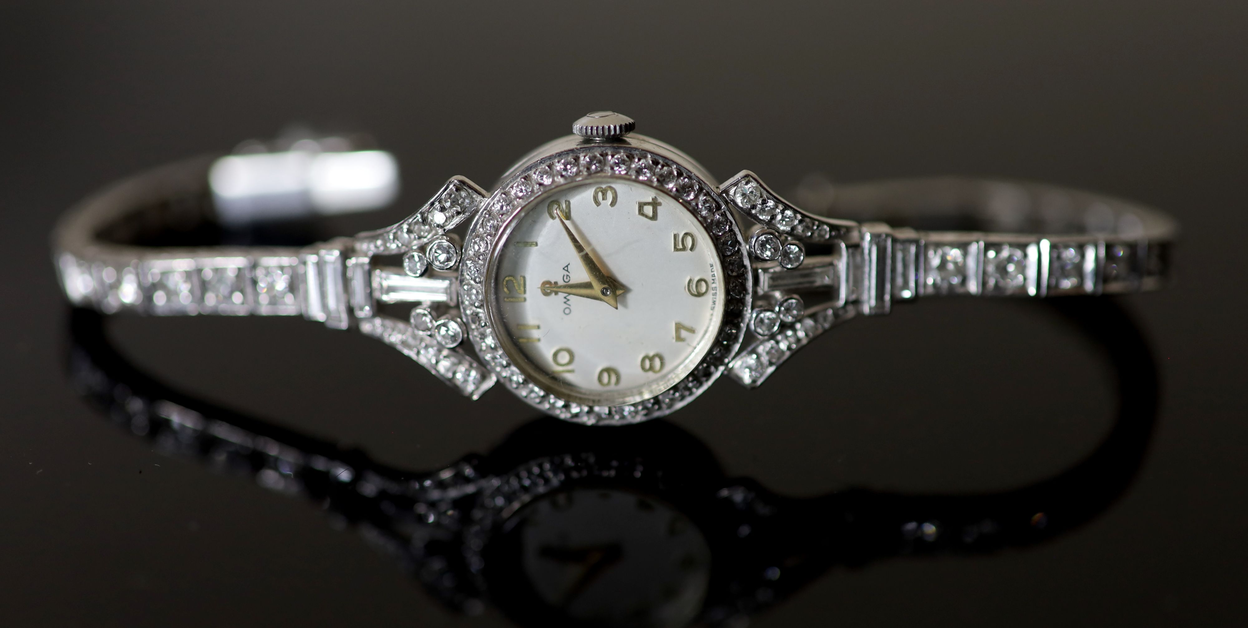 A ladys early 1960s 18ct gold, palladium and diamond set Omega manual wind cocktail watch, on diamond set bracelet,